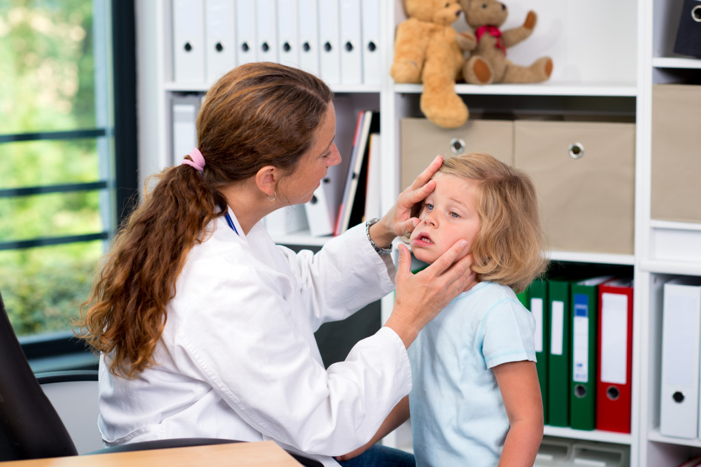 female pediatrician in white lab coat examined little patient